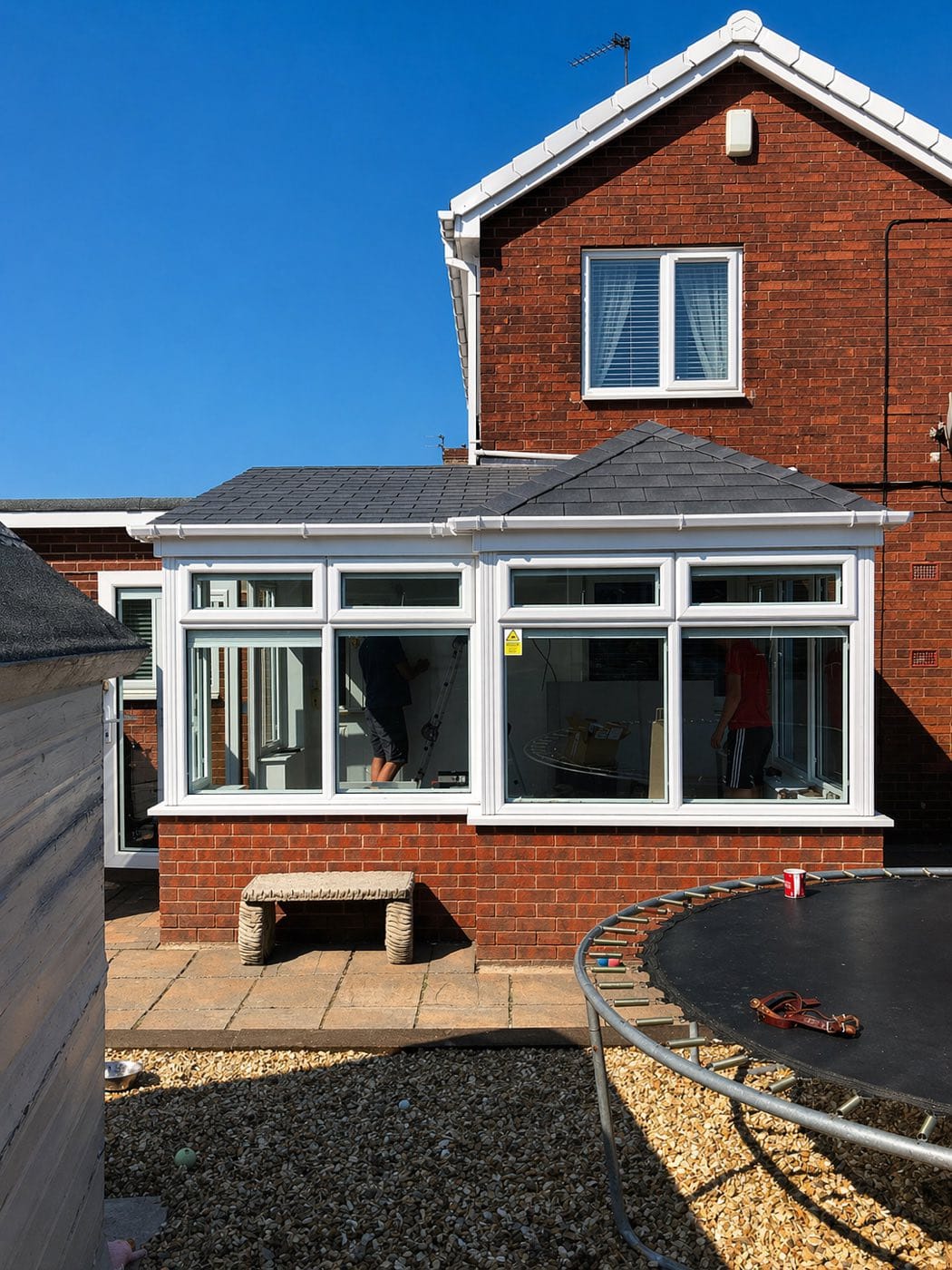 Two fitters working inside a conservatory that has had its new dark grey tiled roof completed