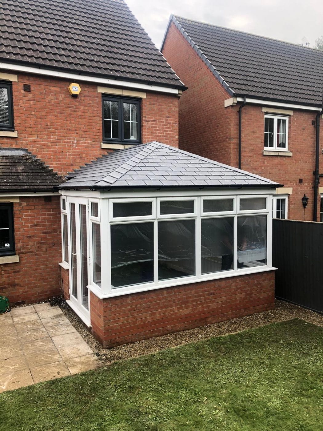 A conservatory with a new grey tiled warm roof on a modern brick house